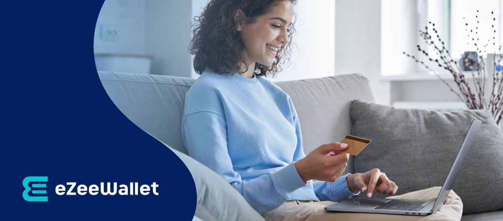 eZeeWallet, nő laptopon vásárol, bankkártyás fizetés, online fizetés, kanapén, digitális pénztárca, biztonságos tranzakció