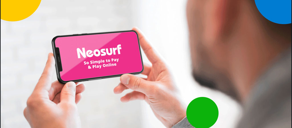 Neosurf logó, So Simple to Pay & Play Online szöveg, okostelefon kijelzőn, férfi kézben tartja, színes körök, online fizetés